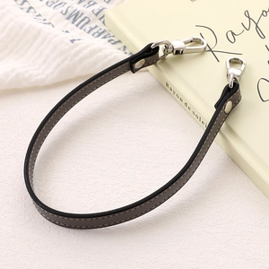 Detail of grey PU leather bag strap with silver metal lobster clasps and smooth edges