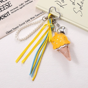 Detail of leather ice cream cone bag charm with pearl chain and heart metal buckle