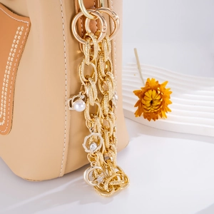 Golden multi-layer bag chain with star and pearl charms on beige leather purse