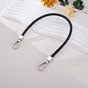 Detail of hand-woven black leather bag strap featuring sturdy silver metal swivel snap hooks