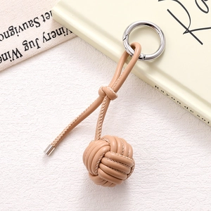 Macro detail of hand-woven leather ball bag charm with premium silver ring buckle