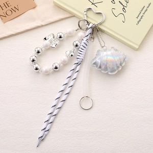 Detail of beaded phone strap with laser shell pendant and silver bow on white texture
