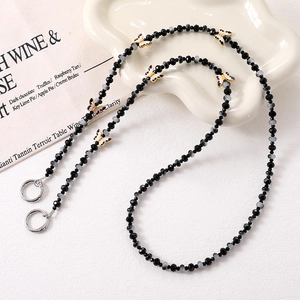 Close-up of beaded crossbody chain featuring butterfly charms and metal spring clasps
