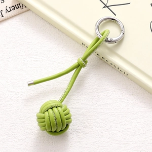 Detailed view of handmade woven leather ball keychain in avocado green with silver ring