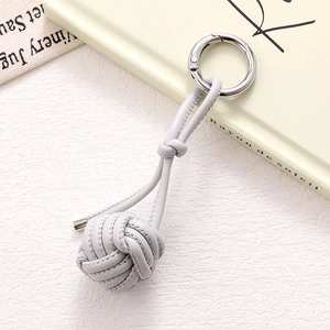 Detail view of a light grey braided leather ball keychain with silver metal spring ring