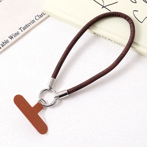 Detailed view of dark brown braided phone strap with premium leather patch and metal ring