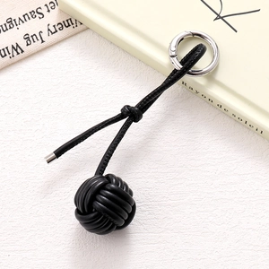 Detailed view of black woven leather ball charm with silver metal ring and cord