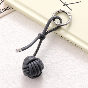 Detail of hand-woven dark gray PU leather ball bag charm with silver metal spring ring