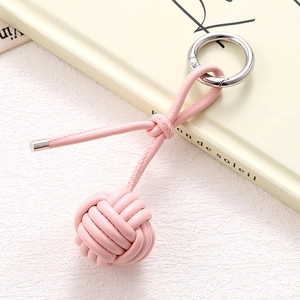 Detail shot of handcrafted pink PU leather woven ball keychain with silver spring buckle