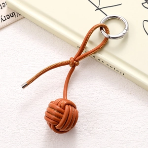 Detail of hand-woven PU leather ball keychain in tan brown with silver metal ring
