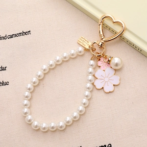 Détail d'un porte-clés perle sakura avec fleur en émail rose et fermoir coeur doré