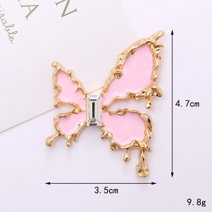 Détail macro d'une breloque papillon en émail rose avec bords dorés et cristal central