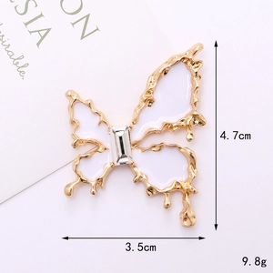 Vue détaillée d'une breloque papillon dorée avec cristaux, dimensions de 4,7 cm sur 3,5 cm