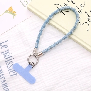 Dettaglio del cinturino da polso in denim azzurro con bordi sfrangiati e paillettes