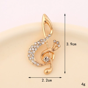 Detailed view of gold musical note pendant with white rhinestones measuring 3.9cm x 2.2cm