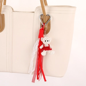Handmade beaded bear bag charm with red lace ribbon and silver heart clip on a tote bag