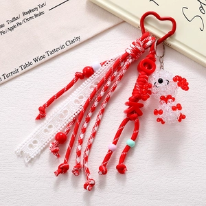 Detail of red and white woven keychain featuring a heart clasp and beaded poodle charm