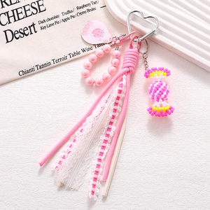 Detail of pink hand-woven candy phone charm with lace ribbon and heart metal clasp