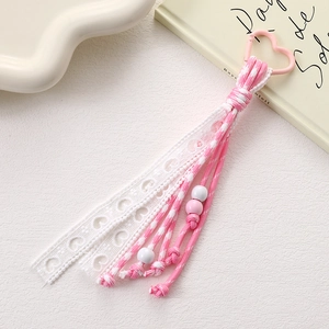 Detail of pink and white woven strap pendant with heart clasp and lace ribbons