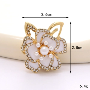 Dettaglio macro della spilla fiore smaltato con perla e strass, misura 2,6 cm per 2,8 cm