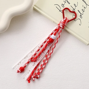Detail of red and white woven phone charm with lace trim and heart metal clasp