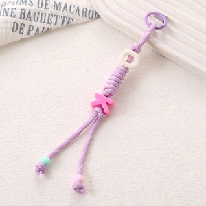 Détail macro du porte-clés en corde de nylon tressée violette avec charme lettre K rose