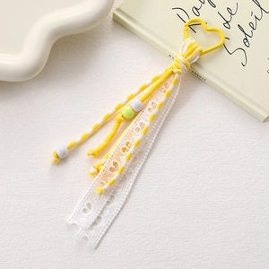 Macro view of handmade yellow lace woven keychain with heart hook and acrylic beads