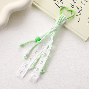 Detail of light green woven cord keychain with heart lace and acrylic beads