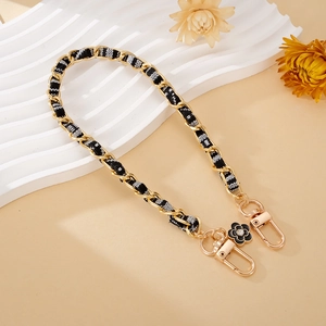 Detail view of woven black and white fabric chain with golden camellia flower charm