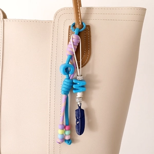 Bijou de sac en nylon tressé avec perles de lettres et pendentif plume bleue sur sac