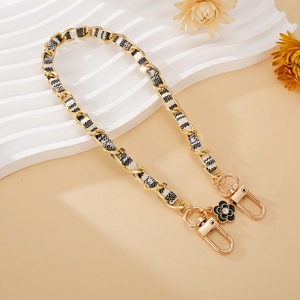 Detail of woven gold chain with black white plaid fabric and crystal flower charm