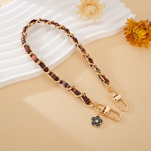 Close-up of gold metal chain with tweed ribbon and camellia flower pendant detail