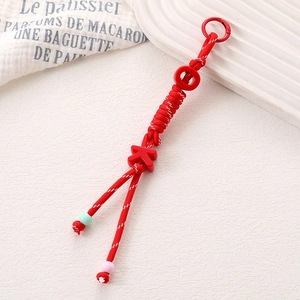 Détail d'un porte-clés tressé rouge avec perles de lettres OK et accents pastel fins