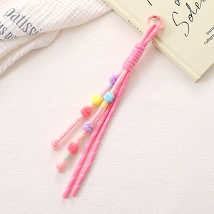 Macro detail of hand-woven pink rope keychain with colorful decorative knots