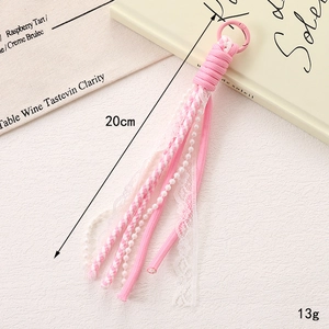 Détail de breloque de sac en dentelle rose avec perles blanches et mousqueton assorti