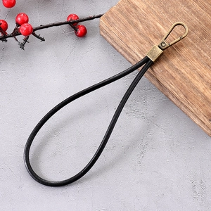 Close-up of black leather wrist strap with retro bronze metal clasps on a textured surface