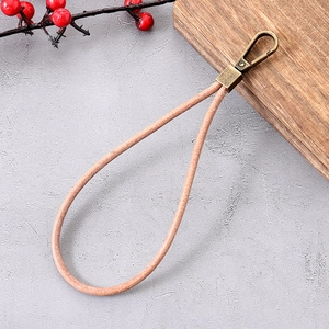 Pink leather wrist strap phone chain with bronze metal lobster clasp on stone surface