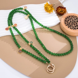 Detail of green glass beads with gold-rimmed enamel flower pendants on a display