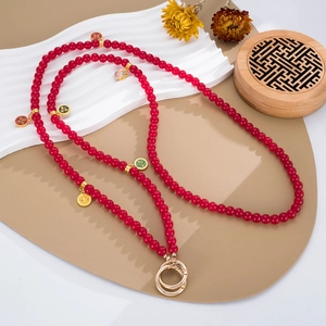 Detail of red beaded phone strap with traditional enamel pendants and gold metal buckles