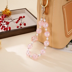 Bijou de téléphone avec perles étoiles roses et fausses perles sur un sac beige