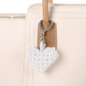 Elegant handmade white pearl heart charm with silver clasp on beige leather handbag
