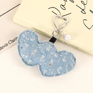 Detail eines Pailletten-Denim Herz-Anhängers mit silbernem Verschluss und Perle