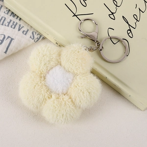 Detail of plush flower charm with yellow petals, white center, and silver metal clasp