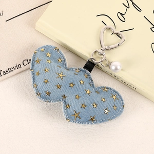 Detail eines blauen Herz-Schlüsselanhängers aus Denim mit Sternen und Perlenanhänger
