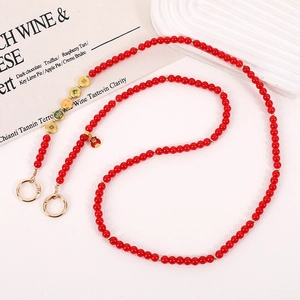 Macro view of red beaded phone strap with gold charms and Chinese fortune pendant