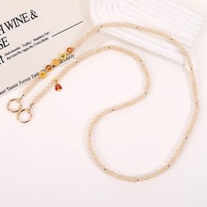 Detail of beaded mobile chain with gold accents and lucky red fortune bag charm