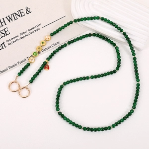 Detail of green beaded phone strap with lucky Fu pendant and gold clasps