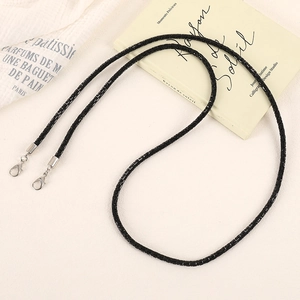 Detail of a sparkling black beaded phone strap with silver lobster clasps on a soft fabric