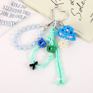 Close-up of handmade beaded mushroom charm with letter beads and a heart clasp