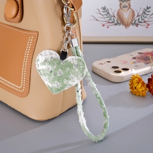 Close-up of heart-shaped green plaid charm with sequins on a brown leather bag